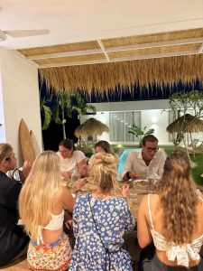 A group of people are enjoying dinner together in the dining area at Balisurfcamp Kavomaison.