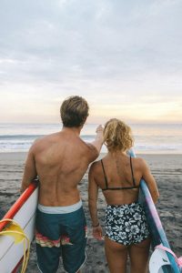 A moment of a couple enjoying a surf trip together at the beach during sunset or sunrise.