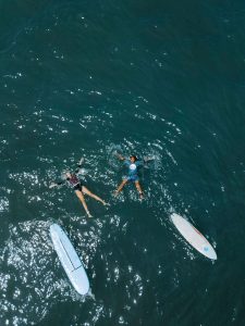 two people are relaxing in the sea water with surfboards