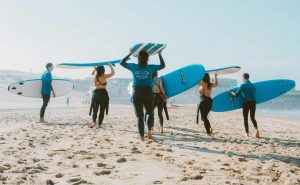 A group of people on a sandy beach getting ready to surf