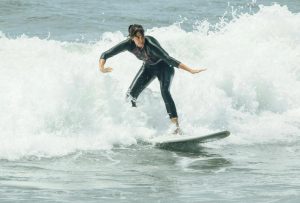 A woman standing and maintaning her balance on a surfboard