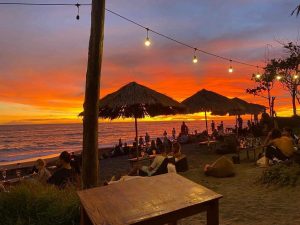 Beautiful sunset atmosphere in a beachside cafe or bar with several people enjoying the sunset view