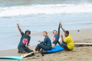 A group of four people on the beach with their surfboards
