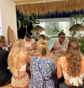 A group of people are enjoying dinner together in the dining area at balisurfcamp Kavomaison