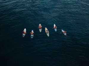 A view from above of several people on surfboards out in the open sea