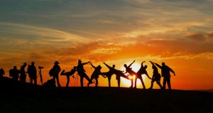 Silhouettes of a group of people posing in the middle of a sunset scene