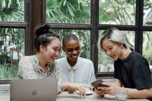 Three young adults are gathering and interacting in a cafe