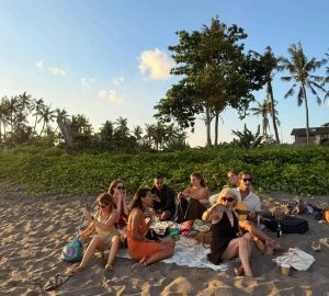 A group of people having a picnic on the beach in the late afternoon or just before sunset