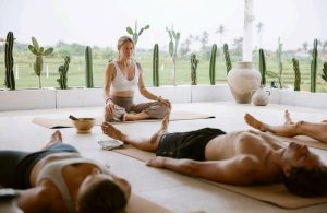 A group of people engaged in a meditation session in an open-air studio with a peaceful atmosphere