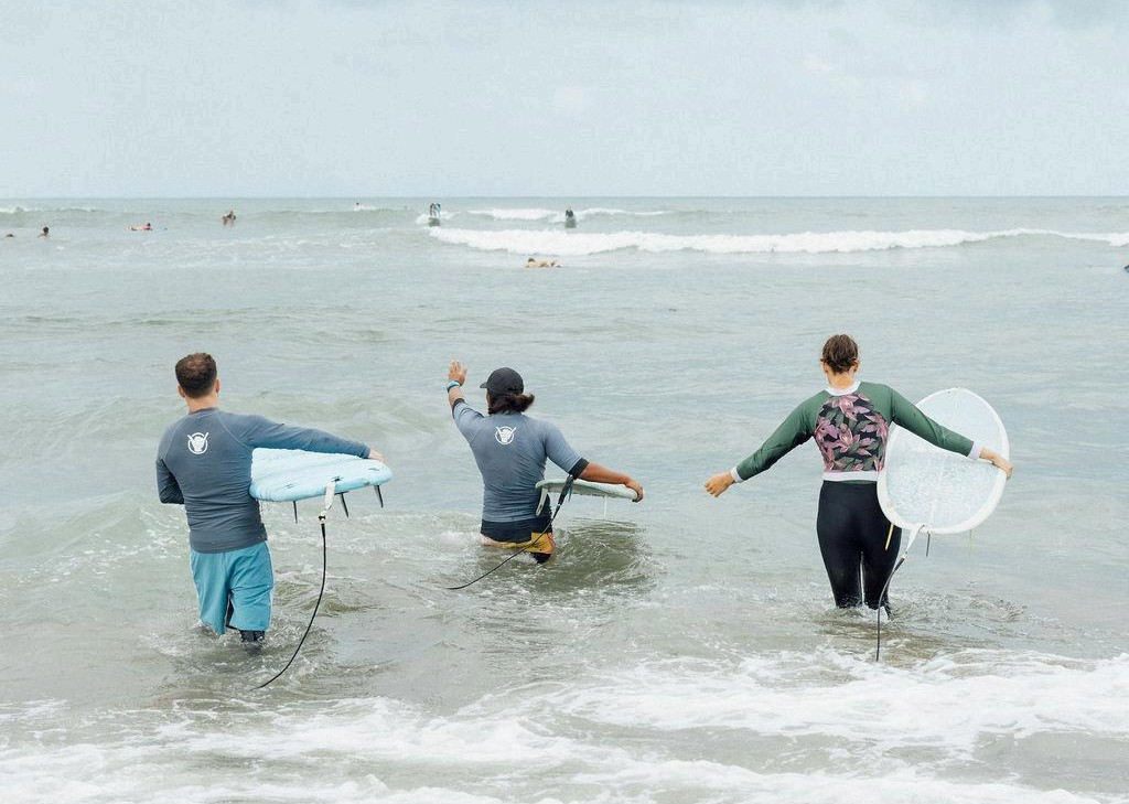 A group of people who are preparing to surf on a beach
