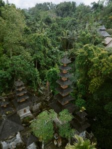 A view from atop a Hindu temple in Bali, surrounded by lush green forest and featuring the temple’s distinctive tiered-roofed meru towers