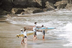 People standing with surfboards on a sandy beach 
