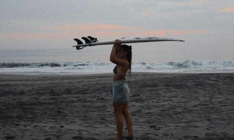 A female surfer standing on a beach
