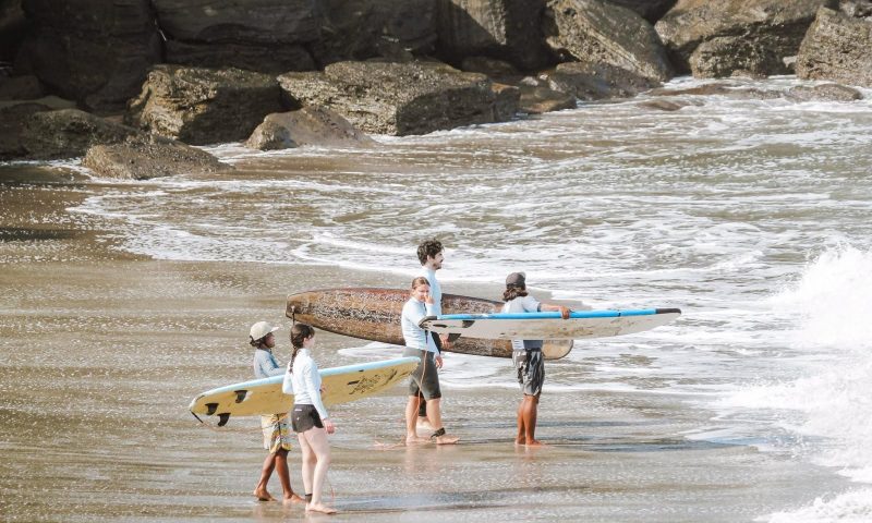 People standing with surfboards on a sandy beach